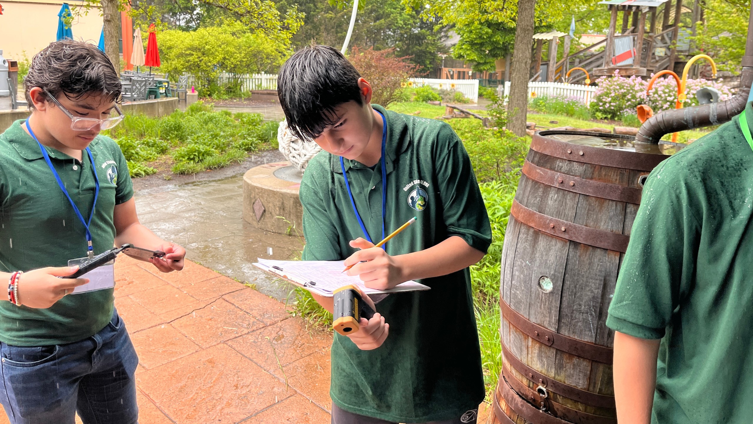 a student holds a clipboard and writes with a pencil on a data sheet while collecting GLOBE surface temperature measurements